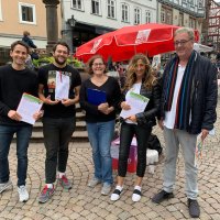 Eine Gruppe Menschen sammelt in der Marburger Oberstadt Unterschriften für den Rückkauf des UKGM